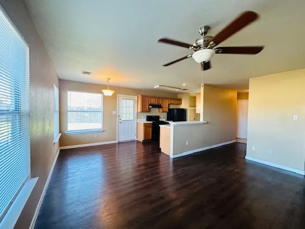 a view of an empty room with wooden floor and a window