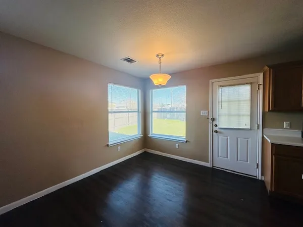 an empty room with wooden floor and windows