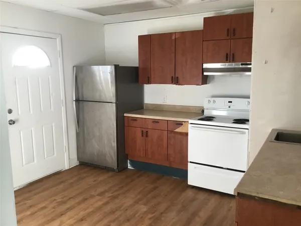 a kitchen with a refrigerator a stove and wooden floor
