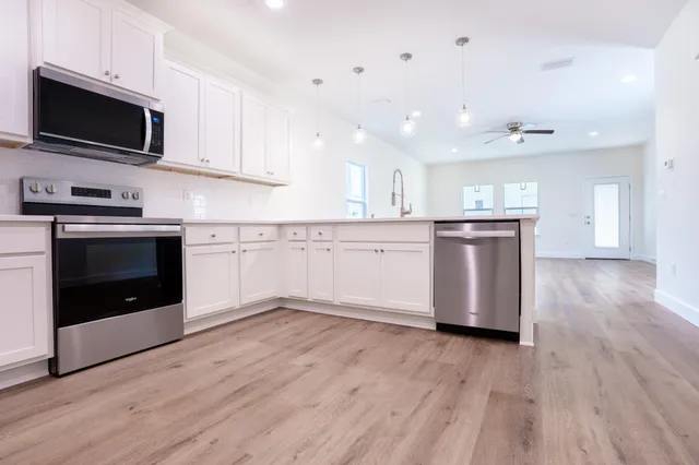 a kitchen with stainless steel appliances granite countertop a stove top oven a sink and a microwave