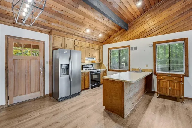 a kitchen with stainless steel appliances granite countertop a refrigerator a sink a stove and wooden floors