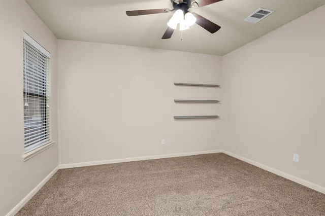 an empty room with a chandelier fan and windows
