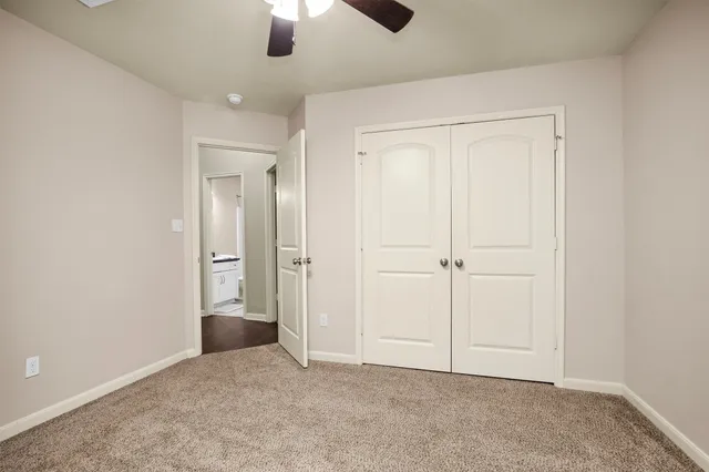 an empty room with fan closet and windows