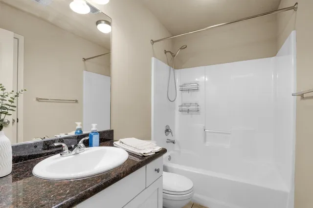 a bathroom with a granite countertop sink toilet a mirror and shower