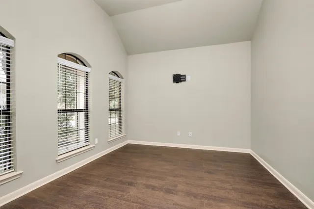 a view of an empty room with wooden floor and windows