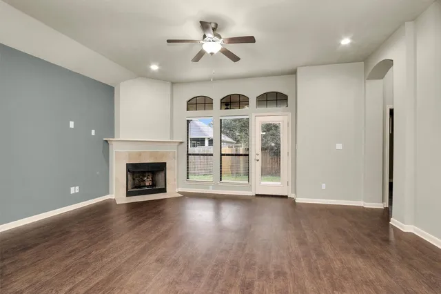 an empty room with windows fireplace and a kitchen view