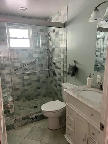 a bathroom with a granite countertop toilet a sink a mirror and shower