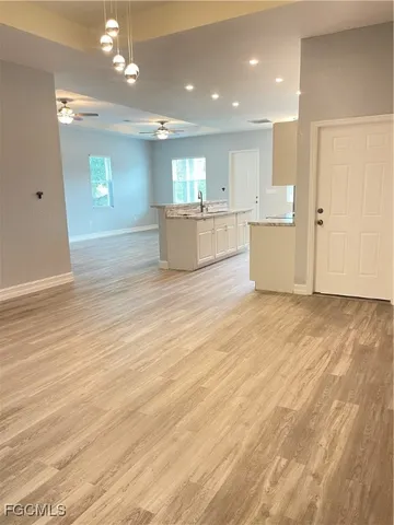 a view of kitchen and empty room with wooden floor