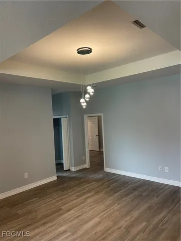 an empty room with wooden floor and chandelier fan