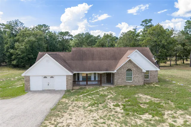 a view of a house with a yard and large tree