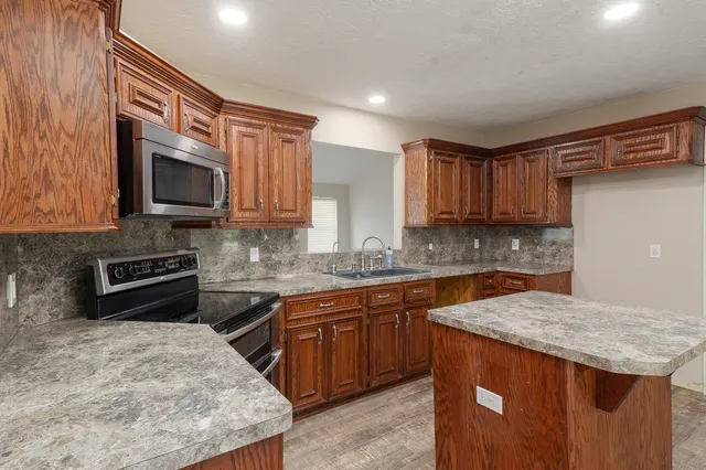 a kitchen with stainless steel appliances granite countertop wooden cabinets a stove top oven a sink and dishwasher