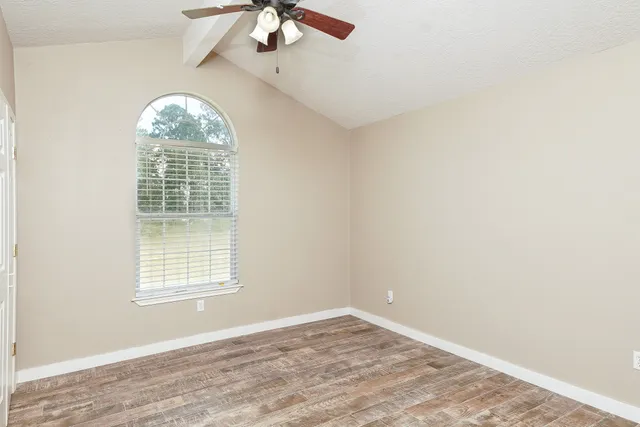 an empty room with a window and a fan