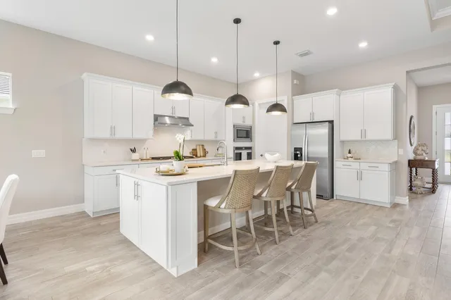 a kitchen with stainless steel appliances kitchen island granite countertop a sink a stove a refrigerator and island with wooden floor