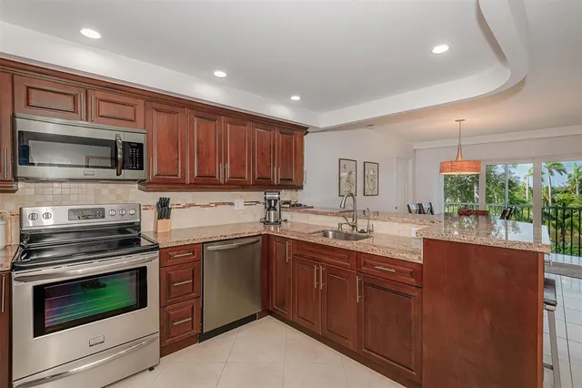 a kitchen with granite countertop a stove top oven a sink dishwasher and a microwave oven with wooden cabinets