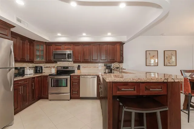 a kitchen with stainless steel appliances granite countertop a sink and a refrigerator