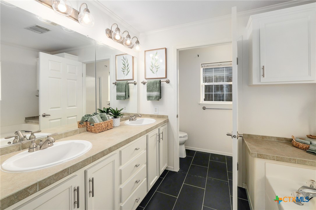 4607 Cedar Point Drive Austin, TX 78723 - Photo 11 of 27 a spacious bathroom with a double vanity sink a mirror and a shower