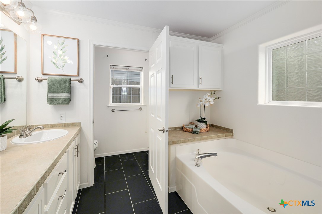 4607 Cedar Point Drive Austin, TX 78723 - Photo 12 of 27 a bathroom with a granite countertop sink and a bathtub