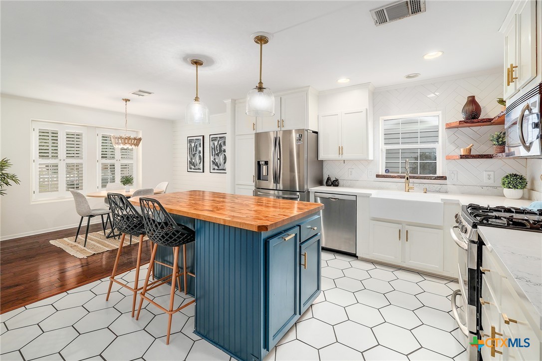 4607 Cedar Point Drive Austin, TX 78723 - Photo 7 of 27 a kitchen with a stove a sink a dining table and chairs