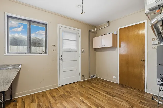 a view of an empty room with wooden floor and a bathroom