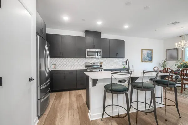 a kitchen with stainless steel appliances a stove a refrigerator and a dining table