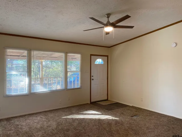 an empty room with window and ceiling fan