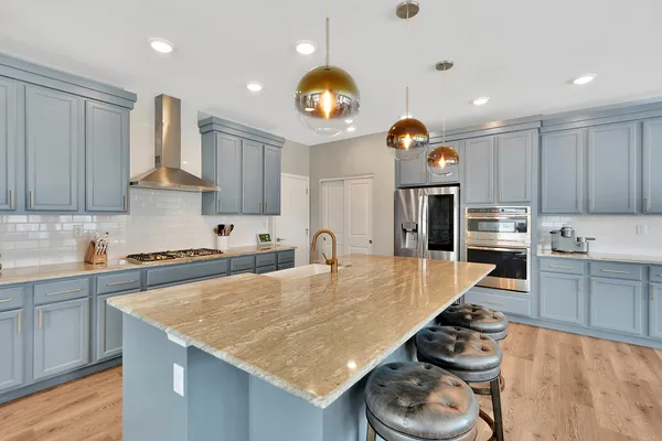 a large living room with stainless steel appliances granite countertop couches a fireplace with wooden floor and windows