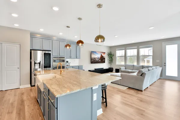 a large kitchen with kitchen island a large counter top space a sink appliances and living room view