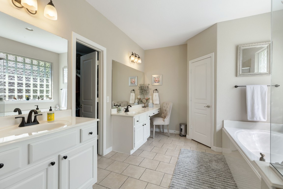 20410 Misty Crossing Lane Spring, TX 77379 - Photo 23 of 50 This spacious bathroom features dual sinks with black fixtures, a large mirror, a comfortable vanity area, and a soaking tub.