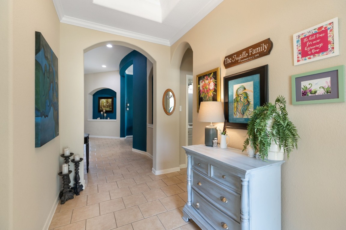 20410 Misty Crossing Lane Spring, TX 77379 - Photo 5 of 50 This welcoming entryway features warm beige walls a decorative arch. The hallway leads to a space with bold blue accents, creating an inviting and artistic atmosphere.