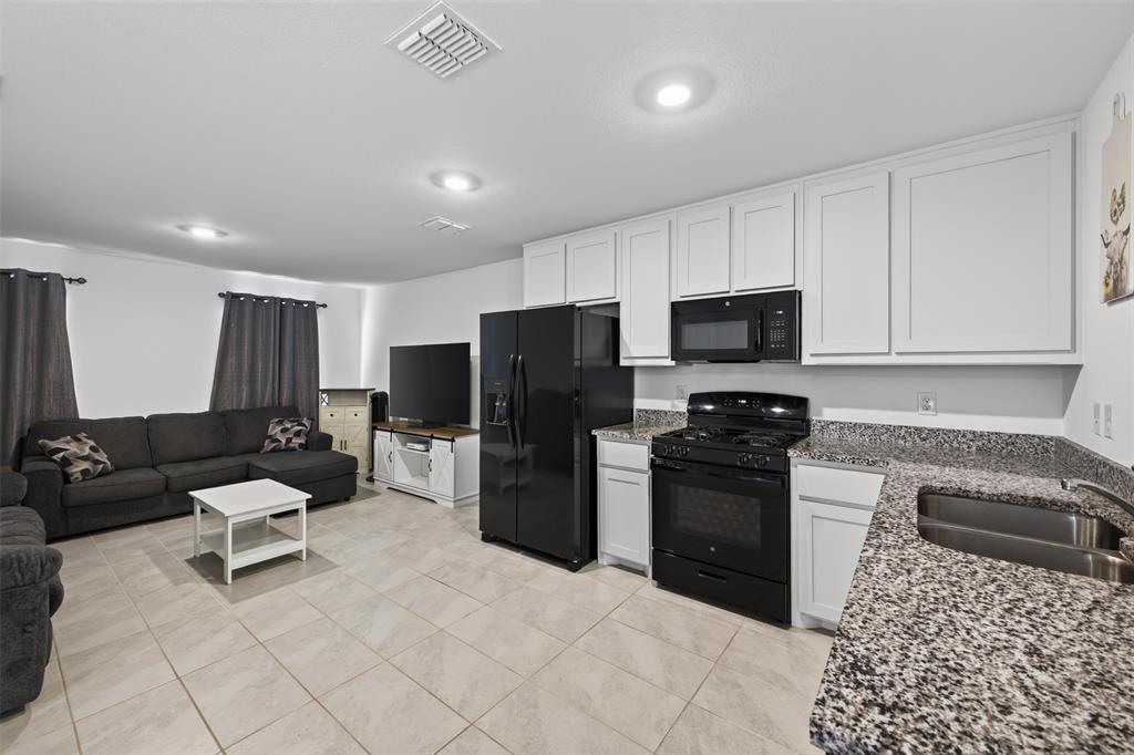 464 Reverie Way Ferris, TX 75125 - Photo 12 of 36 Open-concept living space featuring tiled flooring, recessed lighting, white cabinetry, speckled countertops, and black appliances