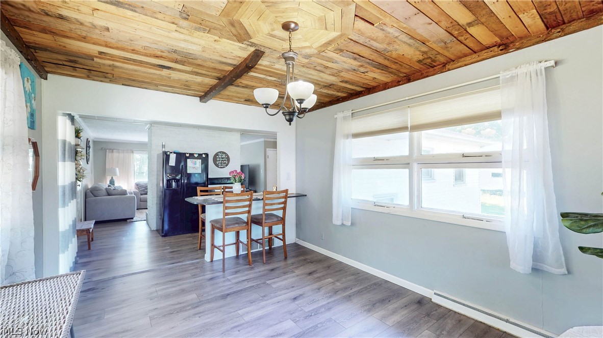3659 Morrow Road Kent, OH 44240 - Photo 16 of 39 Wood-paneled ceiling with exposed beam, large window offering abundant light, wood-finish flooring, and a breakfast bar with built-in cabinetry