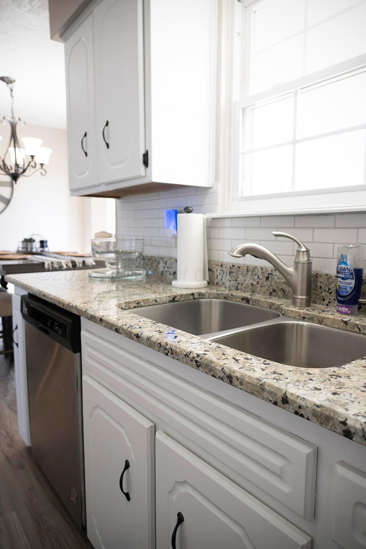 611 Floyd Avenue Dumas, TX 79029 - Photo 12 of 28 a kitchen with granite countertop white cabinets and a sink
