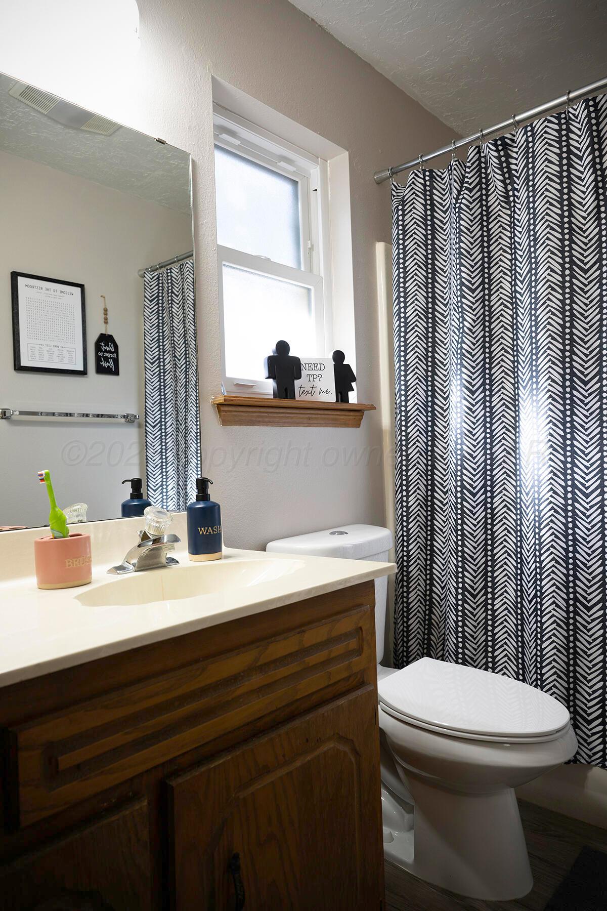 611 Floyd Avenue Dumas, TX 79029 - Photo 16 of 28 a bathroom with a sink a toilet and shower curtain