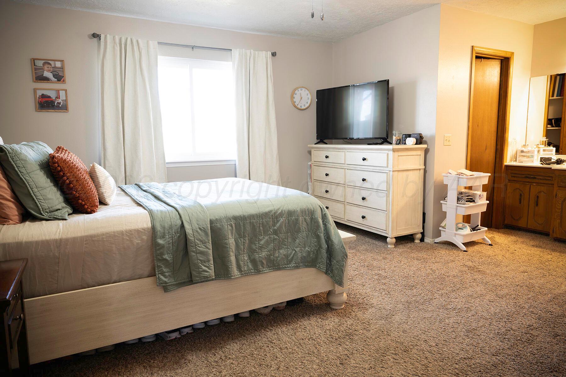 611 Floyd Avenue Dumas, TX 79029 - Photo 20 of 28 a bedroom with a bed and flat tv screen on the dresser