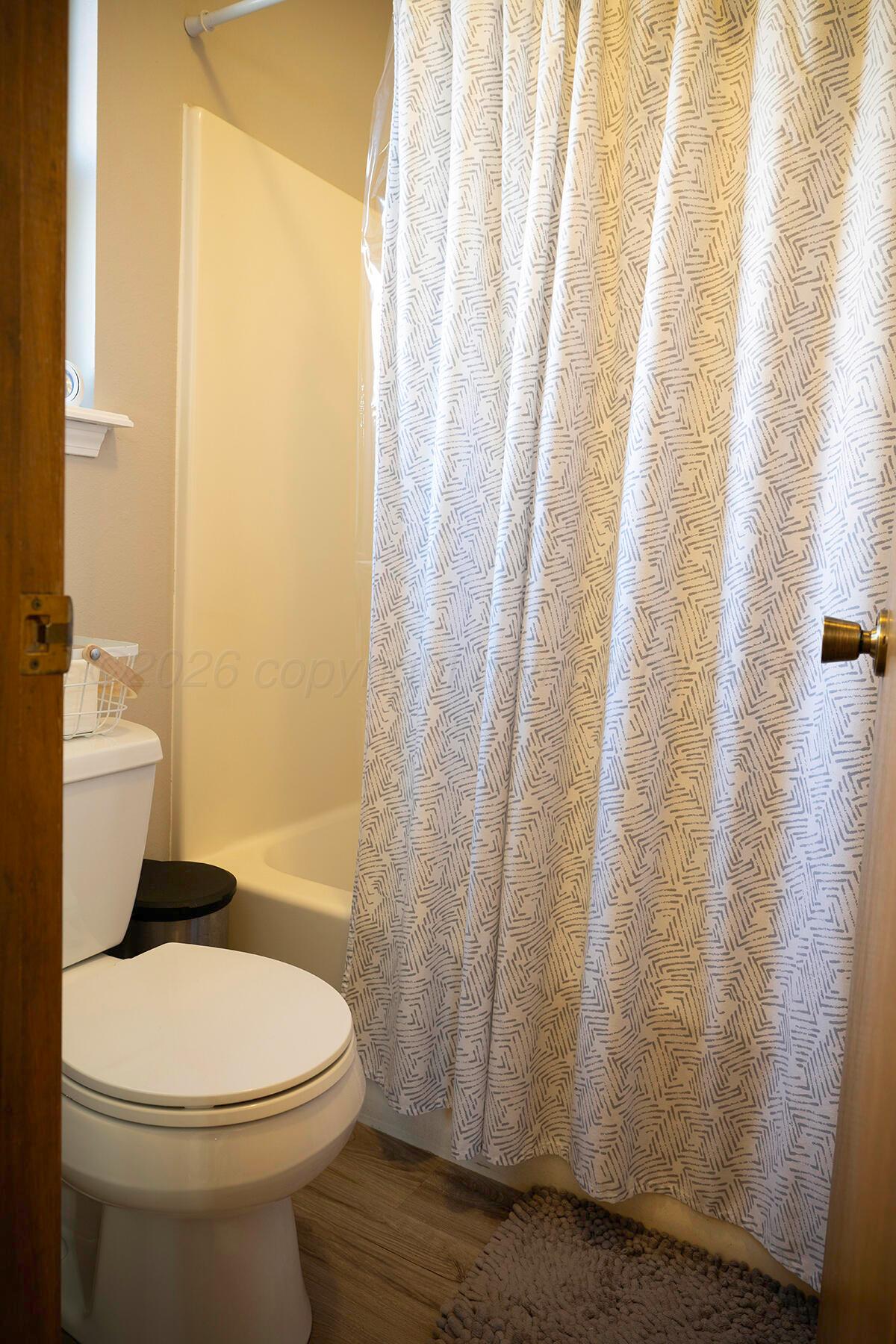 611 Floyd Avenue Dumas, TX 79029 - Photo 22 of 28 a white toilet sitting next to a shower curtain