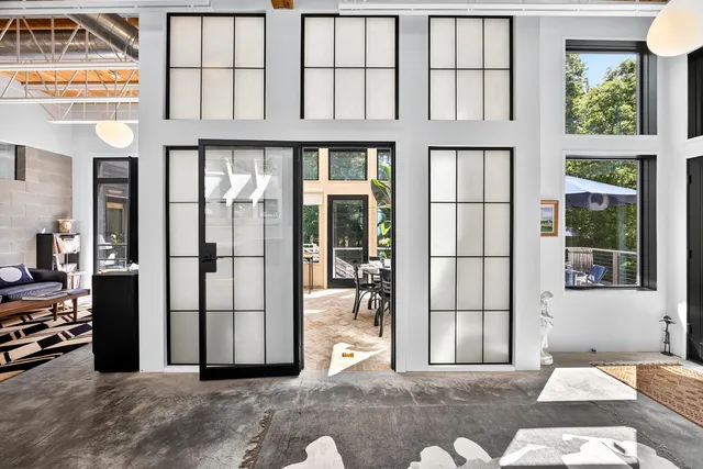 a view of a patio with table and chairs potted plants and floor to ceiling window