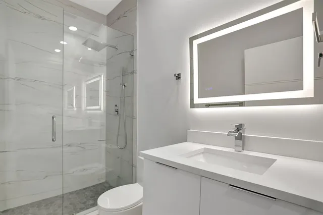 a bathroom with a granite countertop sink toilet and shower