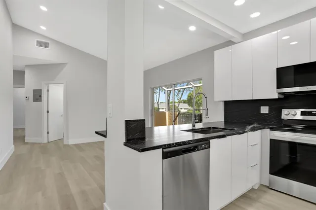 a kitchen with stainless steel appliances kitchen island granite countertop a stove a sink and a microwave