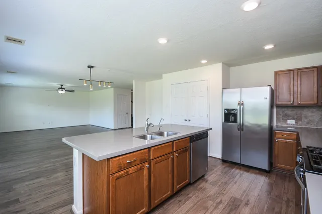 a kitchen with a sink refrigerator and wooden floor