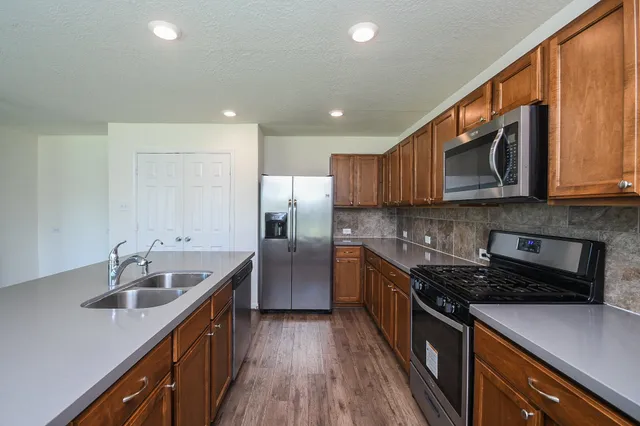a kitchen with stainless steel appliances granite countertop a sink stove and refrigerator