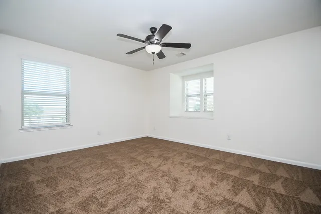an empty room with windows and fan