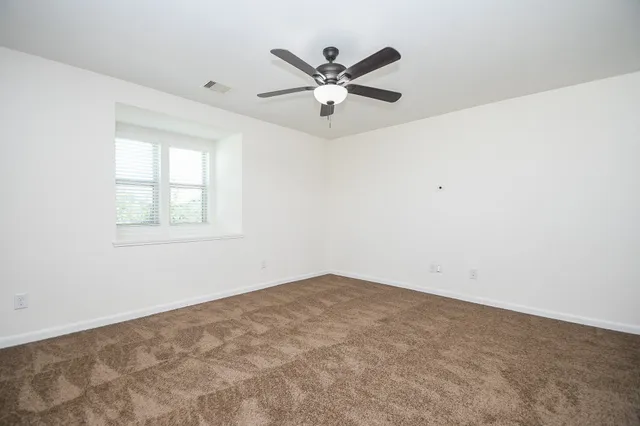 an empty room with window and ceiling fan