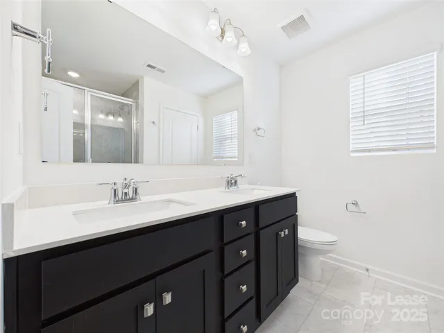 a bathroom with a double vanity sink toilet and a mirror
