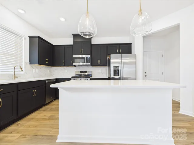 a kitchen with kitchen island granite countertop stainless steel appliances a sink cabinets and microwave