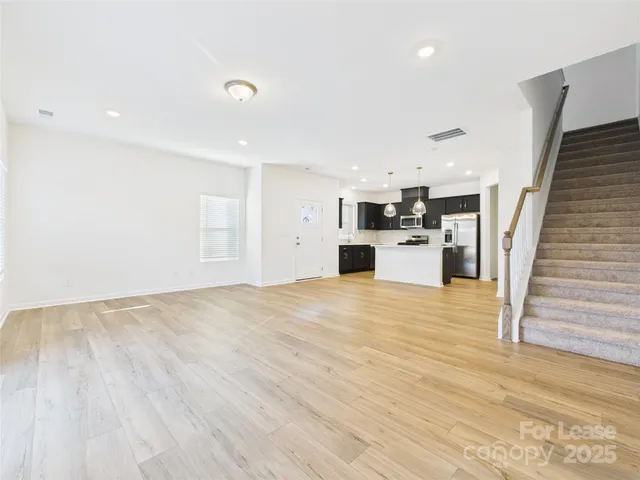 an empty room with kitchen and wooden floor