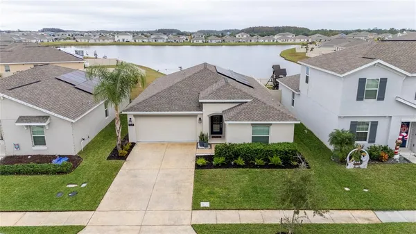 a front view of a house with a garden and lake view