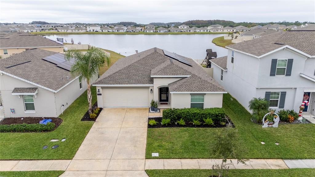 a front view of a house with a garden and lake view