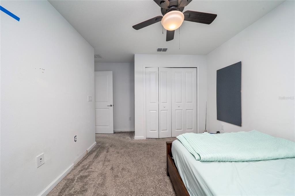 5121 Four Strand Court St. Cloud, FL 34772 - Photo 25 of 26 a bedroom with a bed and a chandelier