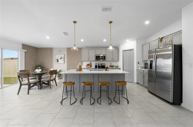 a kitchen with kitchen island a dining table chairs stainless steel appliances and cabinets