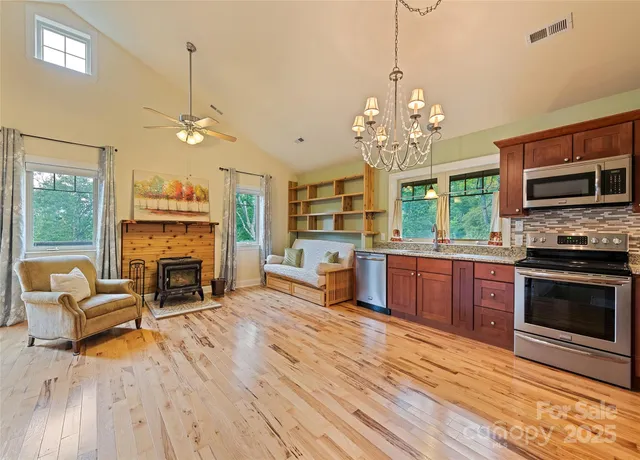 a large living room with stainless steel appliances granite countertop couches fireplace with wooden floor